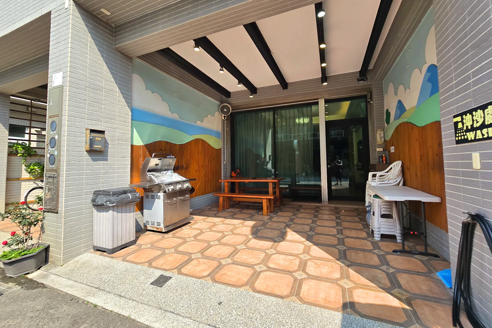 前庭烤肉空間全景，可見烤肉爐、木桌與有遮蔽的戶外區